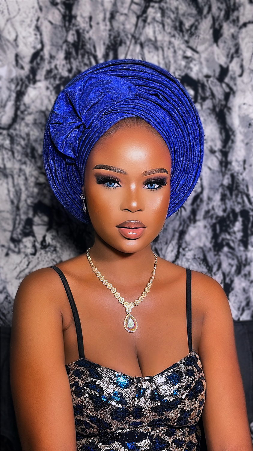 Model in a royal blue pleated gele with blue contact lenses, full-coverage matte skin, glossy ombre lips and a blue-and-gold sequin top